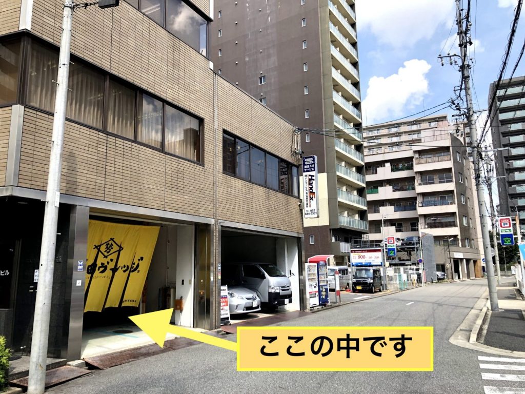 道路から見た千代田ヴィレッジの入口。黄色いのれん「千代田ヴィレッジ」がかかった間口から敷地に入る