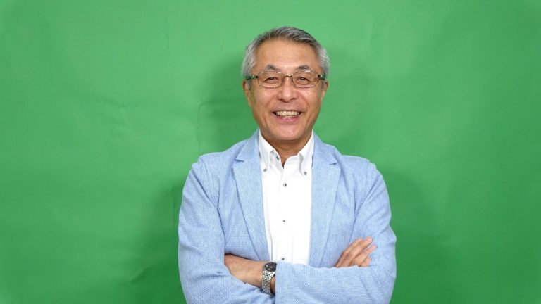 白ホリスタジオのグリーンバック（背景紙グリーン）の前に立つ男性。クロマキー合成用の撮影例