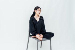 白ホリスタジオでの撮影風景。白い背景の前で椅子に座る人物を撮影したカット