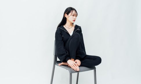 白ホリスタジオでの撮影風景。白い背景の前で椅子に座る人物を撮影したカット